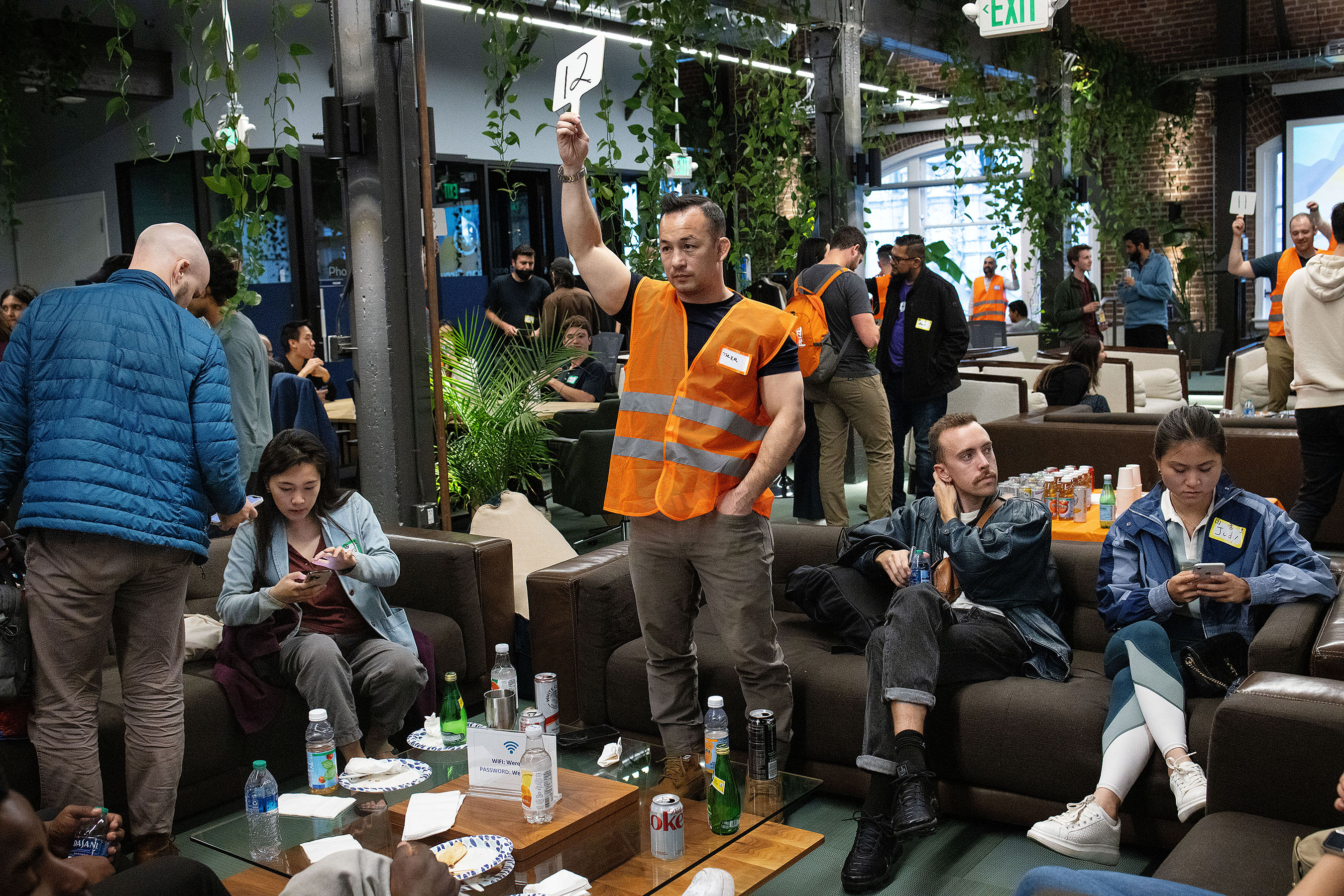 A volunteer at the GAI Collective Summit, a meet-up event, holds up the number of his discussion group to his group knows where to gather at the co-working space Werqwise in San Francisco, Calif., on Tuesday, June 6, 2023. The GAI Collective organizes meet-up events where AI interested individuals gather to discuss the technology of generative AI. At their summit events, attendees are given a number when they check in and these numbers are used to form discussion groups. Throughout the night, the event rotates between small group discussions and then breaking out into networking with the whole crowd. 